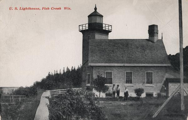 U.S. Lighthouse with people standing in the yard next to it. Caption reads: "U. S. Lighthouse, Fish Creek Wis."