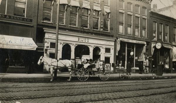 The Bijou Theater with a horse and carriage parked in front of it.  There is a law office above the theater and a jeweler's store beside it.