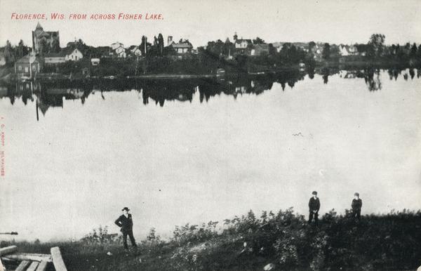 Elevated view of Florence from across Fisher Lake, with several people standing below on the shoreline.
