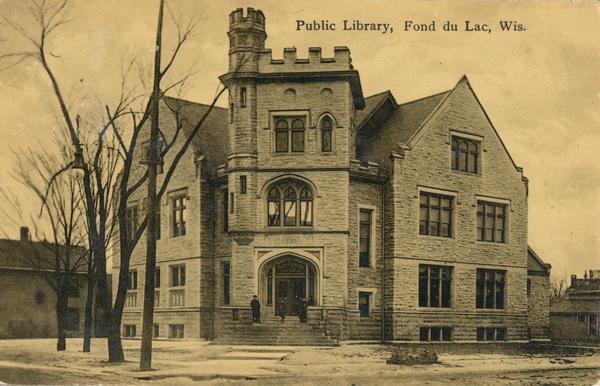 Exterior of the Fond du Lac Public Library, with people standing on the front steps to the building. Caption reads: "Public Library, Fond du Lac, Wis."