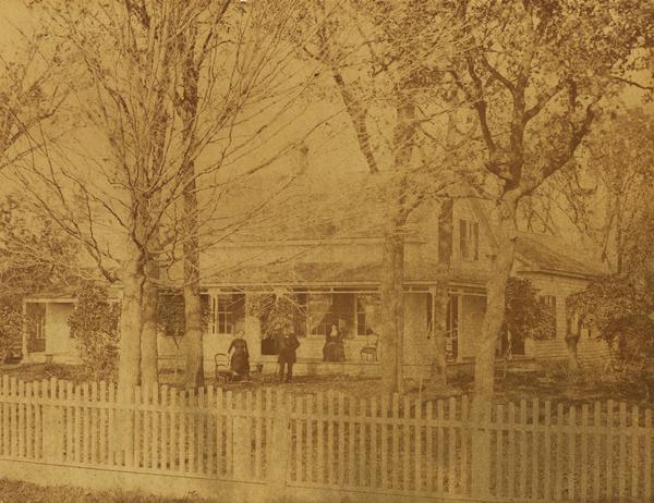 Simmons residence, with people sitting on the porch and standing near the front entrance.