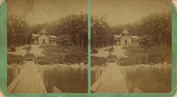 View down pier towards shoreline and building at Lake Geneva at Montague's and Porter's resort, later W.F. Furbecks, at the site of Fontana Park or Buena Vista Park.