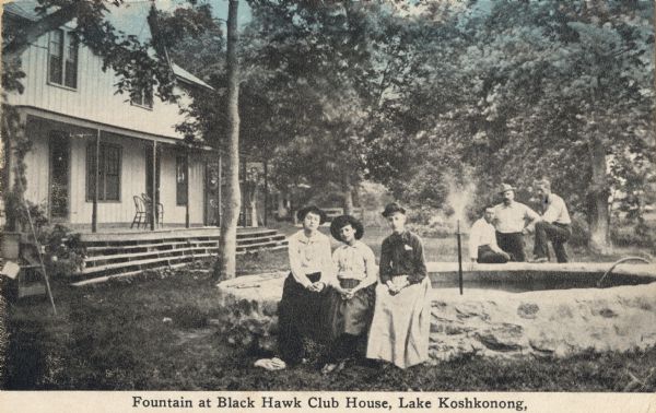 A group of three people are sitting at the fountain, and another group of three people are in the background behind the fountain. Caption reads: "Fountain at Black Hawk Club House, Lake Koshkonong."
