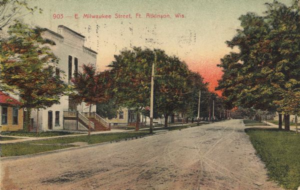 View looking down unpaved East Milwaukee Street in Fort Atkinson. Caption reads: "E. Milwaukee Street, Ft. Atkinson, Wis."