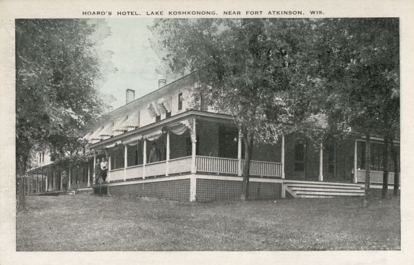 View across lawn toward the Hoard's hotel, with people standing on the wrap-around front porch. Caption reads: "Hoard's Hotel, Lake Koshkonong, Near Fort Atkinson, Wis."
