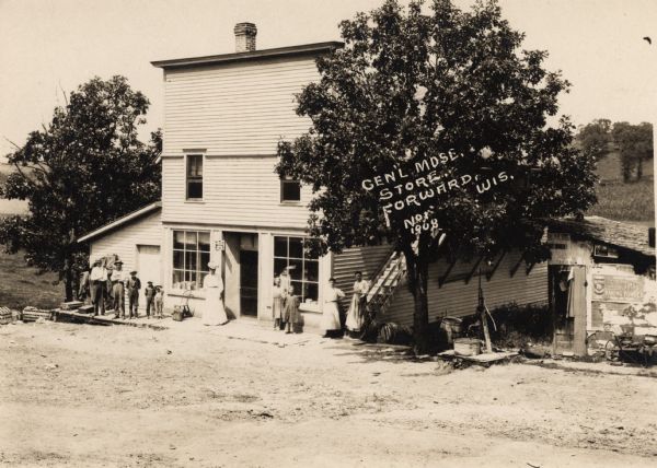 View of the General Store at Forward, Wis., with people standing on the front porch. Caption reads: "Genl Mdse. Store, Forward, Wis."