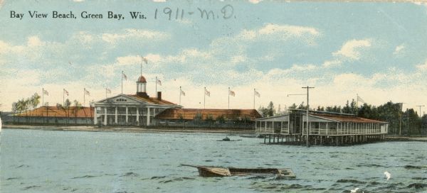 View across water towards Bay View Beach, with several boats in the foreground, and buildings behind them. Caption reads: "Bay View Beach, Green Bay, Wis."