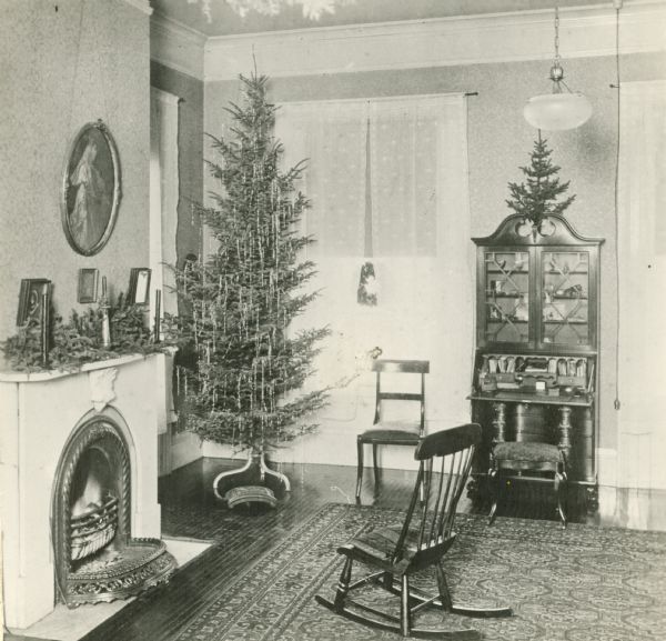 Beaumont House, interior view of parlor with hearth, Christmas tree, rocking chair, and various other decorations.