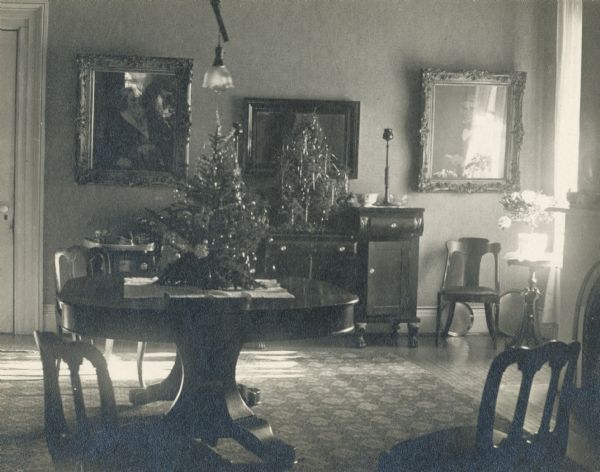 Interior of dining room with a small Christmas tree on top of the dining room table.