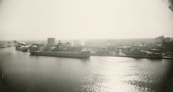 Elevated view of ships sailing up the Fox River alongside the coal yards located in Green Bay.