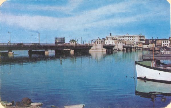 Main Street Bridge. There is a boat in the right foreground, and buildings are along the far shoreline.
