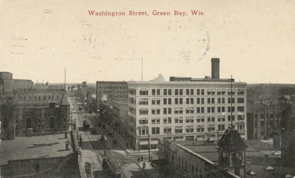 Elevated view of buildings lining Washington Street, with cable cars traveling down the center of the street. Caption reads: "Washington Street, Green Bay, Wis."