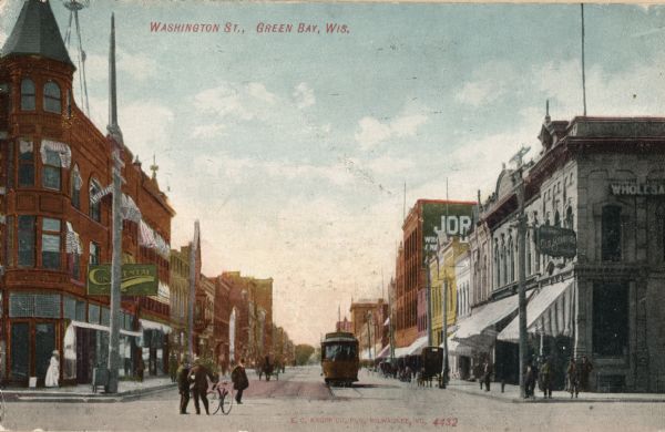 View looking down Washington Street with cable car, bicyclist and pedestrians walking along the sidewalks in downtown area. Caption reads: "Washington Street, Green Bay, Wis."