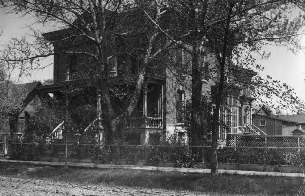 Albert Weise's residence, with wooden sidewalk, and two kids standing on the front porch posing for the photographer.