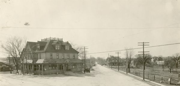 Intersection of Janesville Plan and North Cape Road, with telephone poles lining North Cape Road and cars parked on the side of Schunbrino's Saloon.