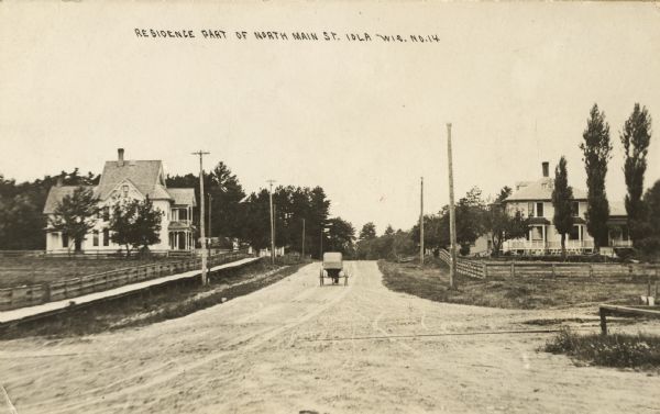 View down unpaved street. Caption reads: "Residence part of North Main St."