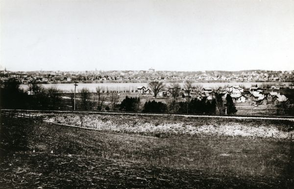 View from the south, with a railroad in the foreground, a river in the middle distance, and Janesville in the background.