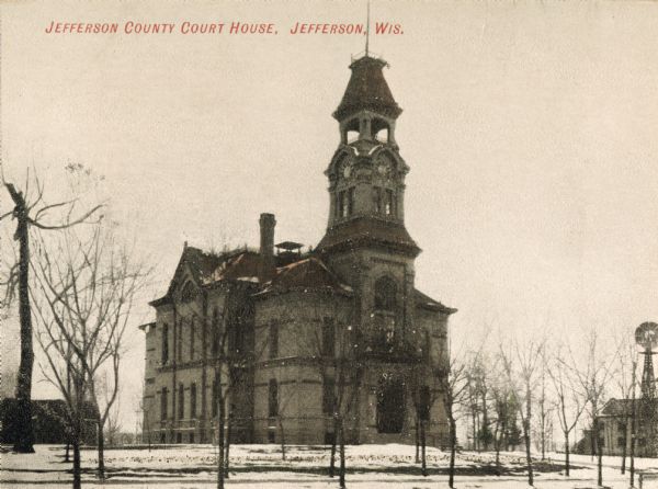 View towards the court house. Snow is on the ground, and a windmill is on the right. Caption reads: "Jefferson County Court House, Jefferson, Wis."