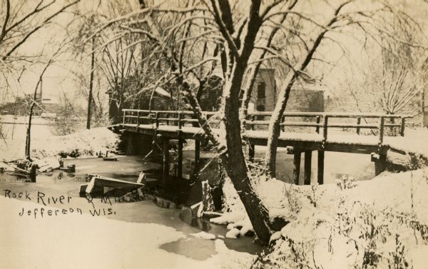 Rock River and Mill Race with bridge. Snow is on the ground and the trees. Caption reads: "Rock River & Mill Race, Jefferson Wis."