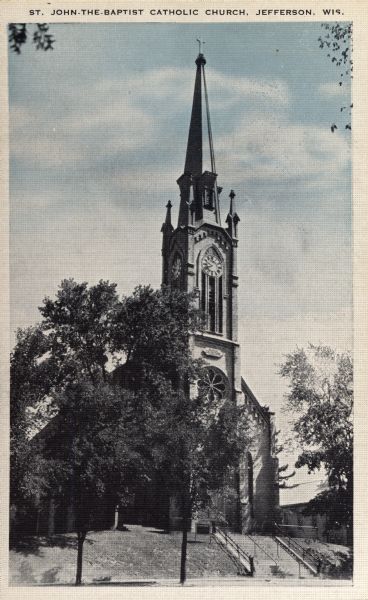 View towards the church on a hill. There is a wide set of stairs that leads up to the entrance. Caption reads: "St. John-the-Baptist Catholic Church, Jefferson, Wis." 