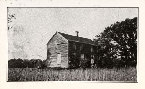 View of the William Wilcox house. The house is set in a field with trees to the right.