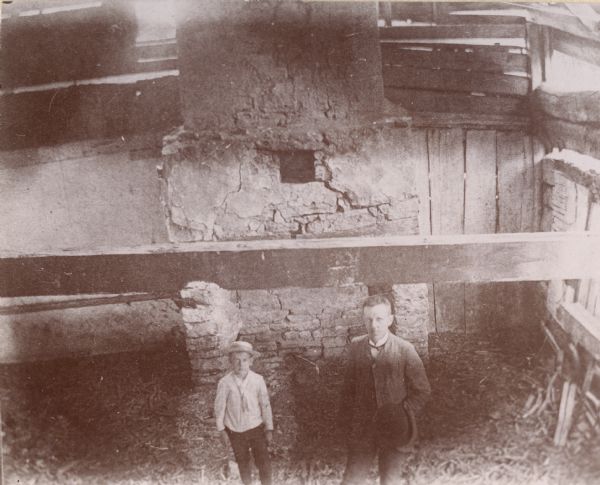 Elevated view of two men in the DuCharme house, later known as the Grignon house.