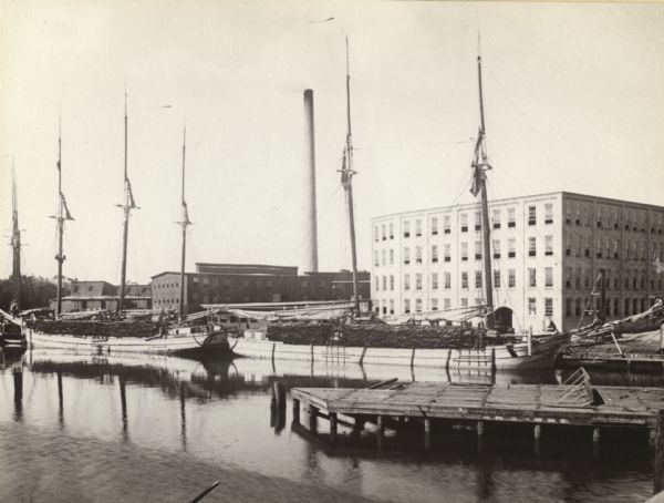 The buildings of Allen & Sons Tannery, with boats carrying supplies in the foreground.