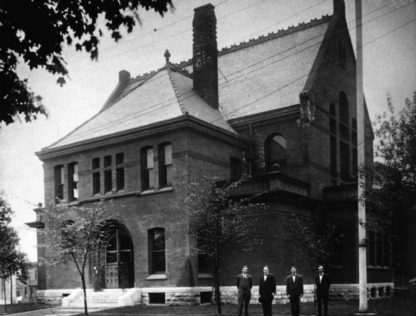 Kenosha County's second Court House located at the southeast corner of Market and Sheridan Road. It was built in 1885 and razed in 1925. Four men are standing in the foreground on the right.