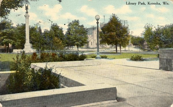 View of plaza with lamppost and a monument on the lawn on the left. Caption reads: "Library Park, Kenosha, Wis."
