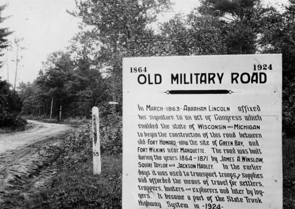 Old Military Road sign. Sign reads: "1864 — 1924 Old Military Road — In March — 1863 — Abraham Lincoln affixed his signature to an act of Congress which enables the state of Wisconsin and Michigan to begin the construction of this road between old Fort Howard — now the site of Green Bay, and Fort Wilkins near Marquette. The road was built during the years 1864-1871 by James A. Winslow, Squire Taylor and Jackson Hadley. In the earlier days it was used to transport troops and supplies and afforded the means of travel for settlers, trappers, hunters and explorers and later by loggers. It became a part of the State Trunk Highway System in —1924—".
