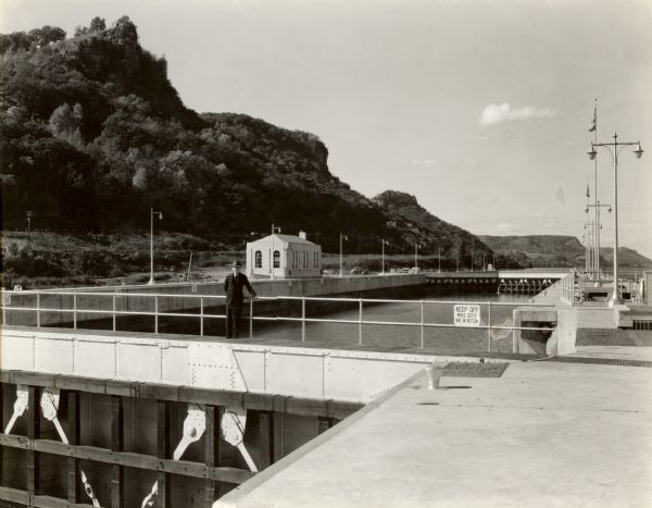 Locks on the Mississippi River, a nine foot channel. A man is standing above the locks. Bluffs are in the background.