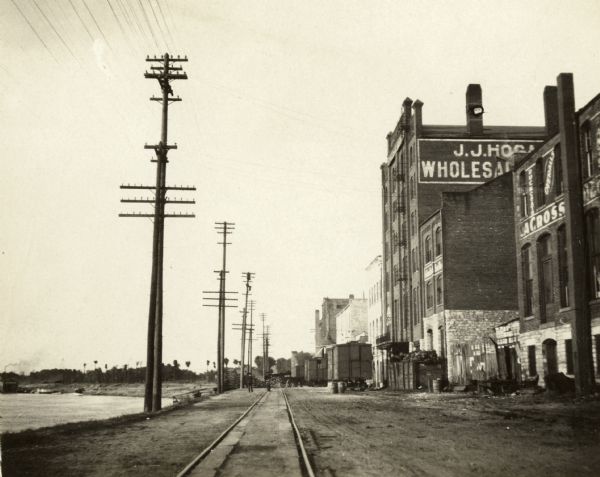 View down railroad tracks, with the Mississippi River on the left, and on the right the J.J. Hogan Wholesale Company.