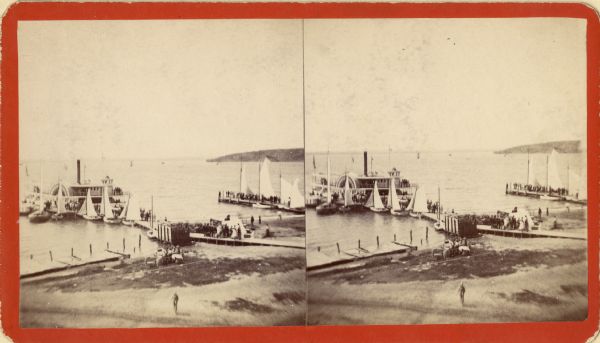 Stereograph elevated view of a steamboat landing in front of the Whiting House. Groups of people are standing on the pier, and more are on the steamboat. Sailboats are lined up along the piers.