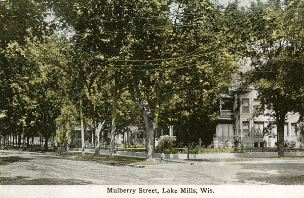 View down street towards houses on the right. Caption reads: "Mulberry Steret, Lake Mills, Wis."