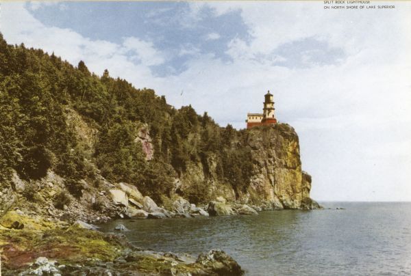 View along rocky shoreline toward the lighthouse. Caption reads: "Split Rock Lighthouse on north shore of Lake Superior."
