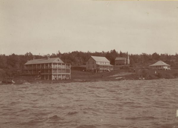View across water towards Old Mission, as seen from the pier with Old Mission Congregational Church behind it. This Mission was established in 1830 by Frederick Ayer, but the buildings date slightly later, and some have been added much later. It later became a resort hotel called Old Mission Inn.