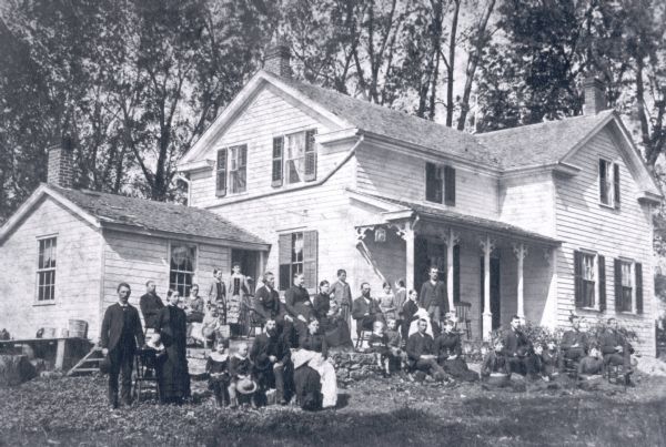 Exterior view of the home of Samuel Rundell, with a large group of people assembled on the lawn in front of the house.