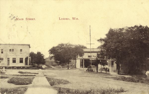 View down sidewalk towards intersection. A hotel is on the left corner. Caption reads: "Main Street. Lomira, Wis."