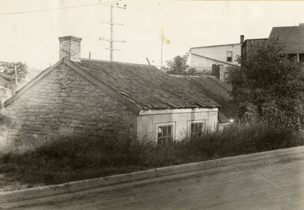 View from road looking down slope toward the house of a Cornish miner. Other buildings are in the background on the right.