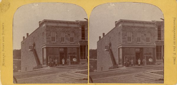 Stereograph of the Martin and Toay Store in Mineral Point. A man is standing at the top of a stairway on the left side of the building. A group of people are standing on the sidewalk in front of the store.