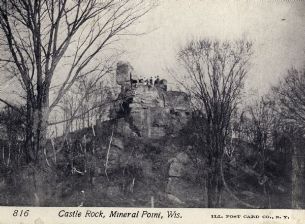 Looking up toward Castle Rock in Mineral Point. A group of people are standing at the top. Caption reads: "Castle Rock, Mineral Point, Wis."