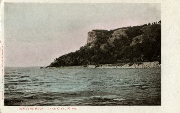 Colorized view of the Maiden's Rock, as viewed from Lake City, Minnesota. This was the legendary lover's leap of Wenonah, the first-born daughter of Dakota Chieftan Wapesha. Caption reads: "Maidens Rock, Lake City, Minn."