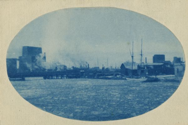 Cyanotype of a river with a two-masted schooner near the shoreline.