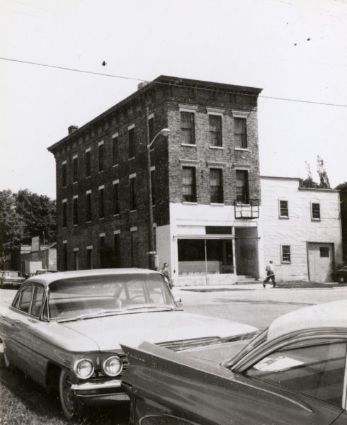 A mercantile building across Sixth Street from the Windiate Hotel, built in 1854. Automobiles are parked in the foreground.