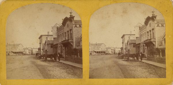 Stereograph of the town square and Main Street. The three-story building in the center was operated as the National Hotel. It was later burned down and was replaced by the Menasha Hotel.