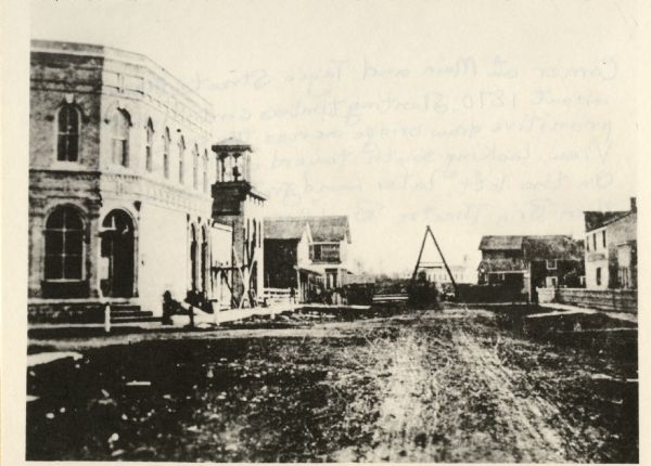 The corner of unpaved Main Street and Tayco Street looking south towards Doty Island. The slanting timbers controlled the primitive draw bridge across the canal.