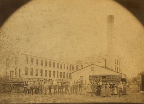The Whiting Paper Mills before it was ruined by fire. A group of men and women are posing in the foreground.