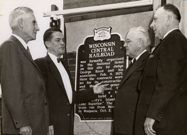 The Wisconsin Central Railroad marker on the wall of the Hotel Menasha. The men at the dedication are (left to right) Edgar F. Zelle, President Wisconsin Central Railroad; Clifford L. Lord, Director of State Historical Society; George Banta, Jr.; Paul Laemmrich, President of Menasha City Council.