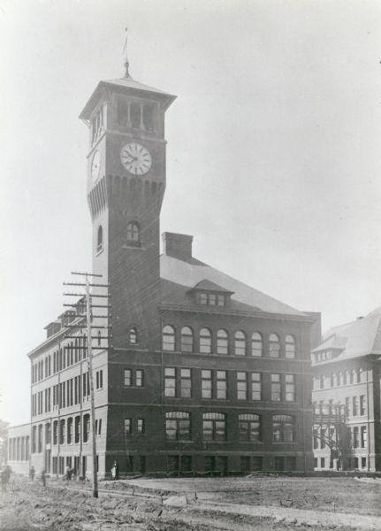 The Stout State College Industrial Arts Building, rebuilt after a fire destroyed the original building in 1897. A clock tower is at the front left corner of the building. The building is now called Bowman Hall.