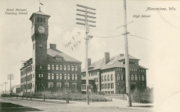 View across street towards the Stout Manual Training School on the left, and the high school on the right. Captions read: "Stout Manual Training School," "Menominee, Wis." and "High School."